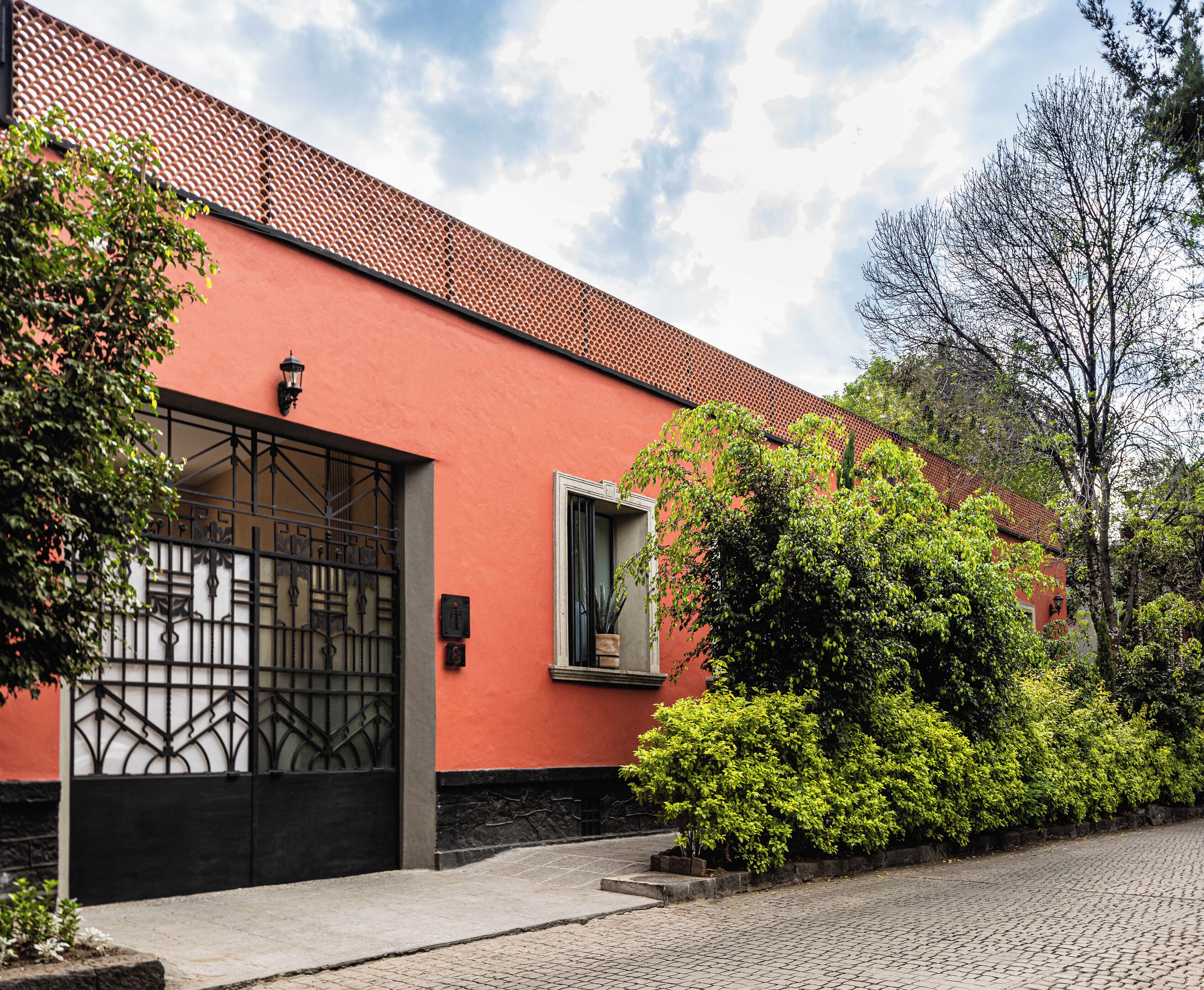 A building with a red facade, a black gate, and a window with a view of the sky.