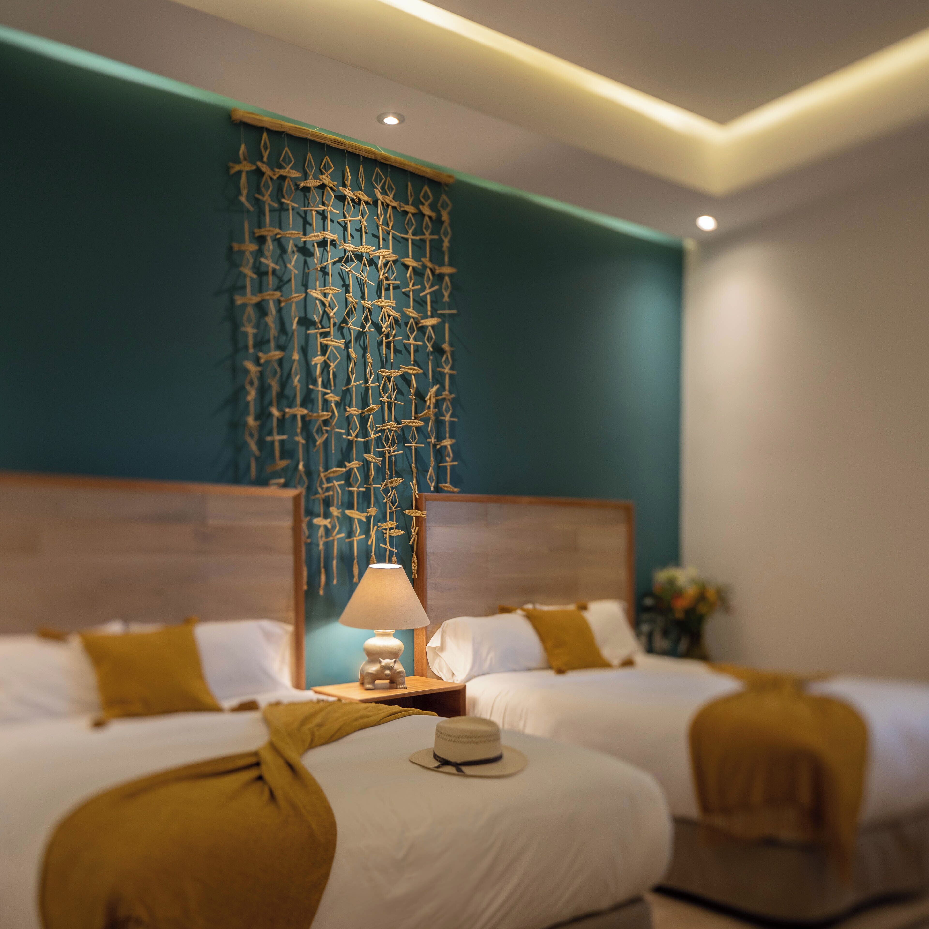 A hotel room with two beds, a wall hanging, and a bedside table with a lamp.