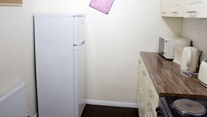 Une cuisine compacte équipée d’un réfrigérateur blanc, d’un four à micro-ondes, d’un grille-pain et d’une cuisinière.