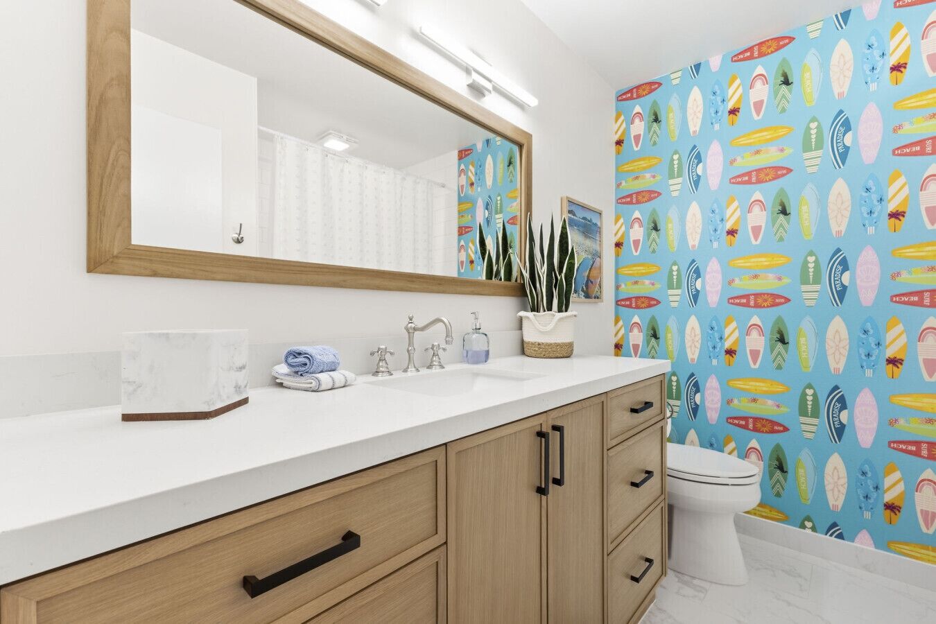 Une salle de bain moderne avec un comptoir blanc, des meubles en bois, un grand miroir et des toilettes.