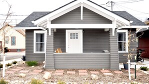 A two-story house with a grey exterior, white trim, and a front porch.
