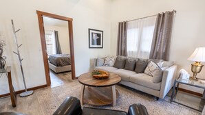 A living room with a sofa, a coffee table, a lamp, and a mirror.