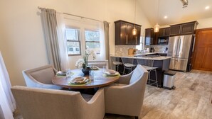 A modern kitchen with dark cabinets, stainless steel appliances, and a dining area with a round table and chairs.