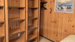 A room with wooden panel walls, a painting of a lighthouse, and a bed with a patterned cover. - COASTAL BREEZE OCEAN CITY Wilmington terrace apartment 4 (Ocean City)