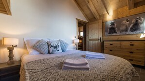 Un dormitorio con una cama grande, techo de madera, cómoda de madera y un cuadro con osos en la pared.