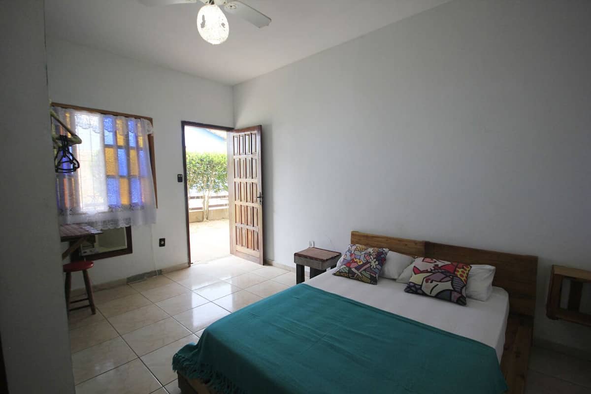 A bedroom with a bed, a desk, and a window with curtains.