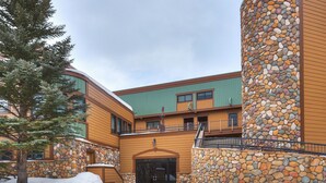 A building with a stone facade, wooden exterior, and a snow-covered ground.