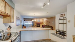 A kitchen with wooden cabinets, a central island, and a dining area with a fireplace.