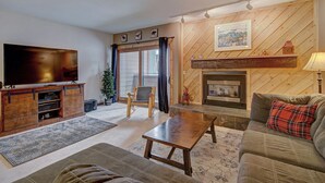 A living room with a television, fireplace, sofa, and a wooden wall.
