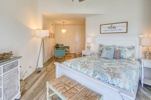 A bedroom with a large bed, a bench, a desk, a chair, and a floor lamp. - 'Salt & Light' Oceanfront Condo w/ Pool & Elevator (Ocean Isle Beach)
