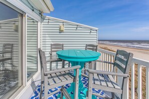 A balcony with a turquoise table and chairs, overlooking a beach. - 'Salt & Light' Oceanfront Condo w/ Pool & Elevator (Ocean Isle Beach)