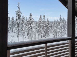 A snowy forest view from a balcony with a railing.