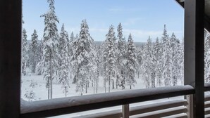A snowy forest view from a balcony with wooden railings.