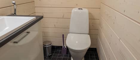 A small bathroom with a white toilet, a sink, and a trash bin.