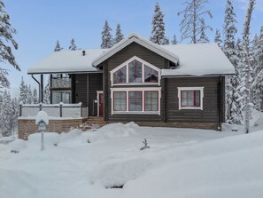 A two-story wooden house with a snow-covered roof and a front porch. - Rölli 2 by Interhome (Äkäslompolo)