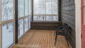 A room with large windows, a wooden floor, and a bench.