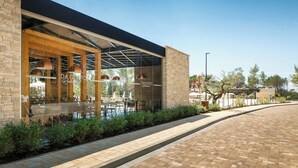 Un espace extérieur moderne, aménagé pour se détendre, avec des murs en briques et des portes en verre, comprenant des tables et des chaises.