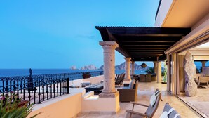 Una terraza con mobiliario exterior, vista al mar y un pilar de piedra.