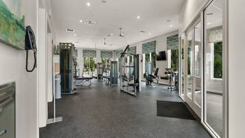 A modern gym with various exercise equipment, large windows, and a clean, well-lit interior.