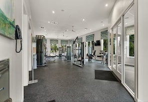 A modern gym with various exercise equipment, large windows, and a clean, well-lit interior. - Luxury 2BR Apt near Disney: Free Water Park, Club House & Stunning Views (Kissimmee)