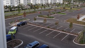Un estacionamiento con varios coches, una señal de stop y un edificio con balcones al fondo.