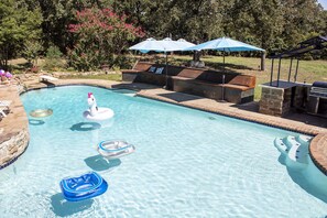 Ein Schwimmbecken mit Luftmatratzen, Liegestühlen und einem Grillplatz.