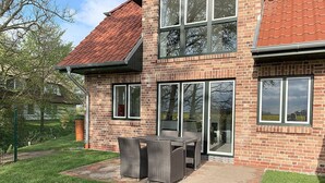 A two-story brick house with a patio and outdoor furniture. - Beacon (Vollerwiek)