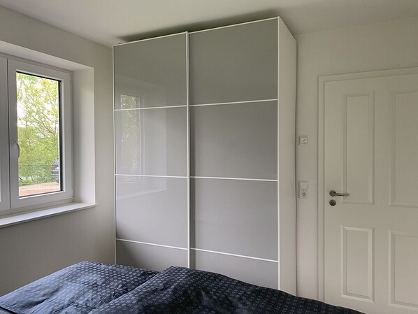 Une chambre à coucher avec un lit, une armoire, une fenêtre et une porte.