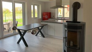 A modern kitchen with a central island, a built-in stove, and large windows. - Beacon (Vollerwiek)