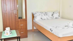 A bedroom with a bed, a wooden wardrobe, and a small table with a cup and saucer. - Charlina Rooms for Rent (Panglao)