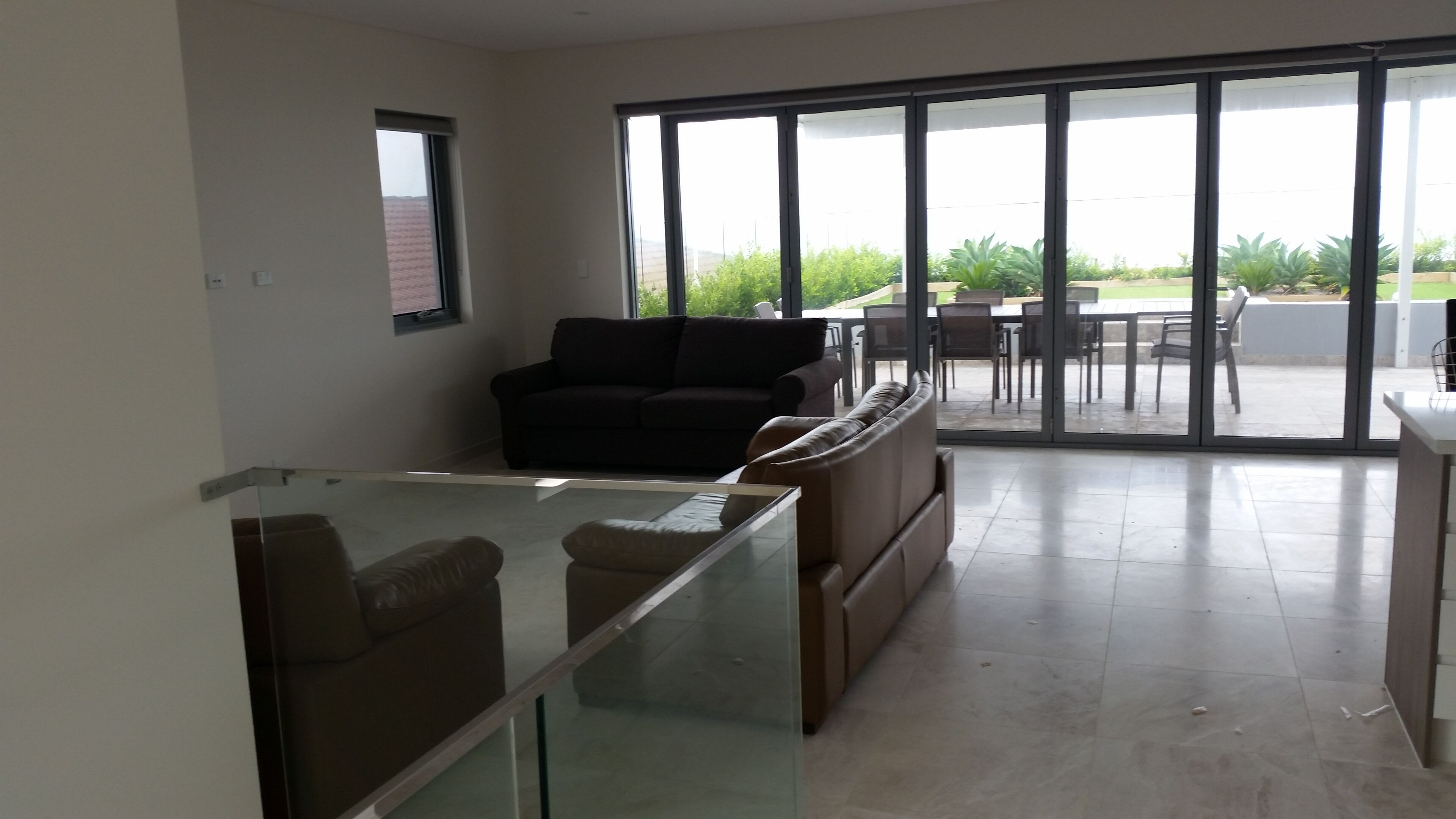 Een ruime woonkamer met een glazen salontafel, een bank en een eethoek met stoelen en een tafel.