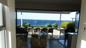 A modern interior with a glass staircase leading to a balcony overlooking the sea. - Beachfront Penthouse The Entrance (The Entrance)