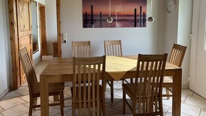 Un coin repas avec une table et des chaises en bois, un tableau au mur et une horloge.