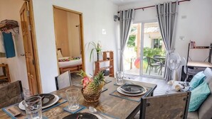 A dining table set with plates, glasses, and chopsticks, a pineapple centerpiece, and a fan in the background. - Enda Lanta Bungalows (Ko Lanta)