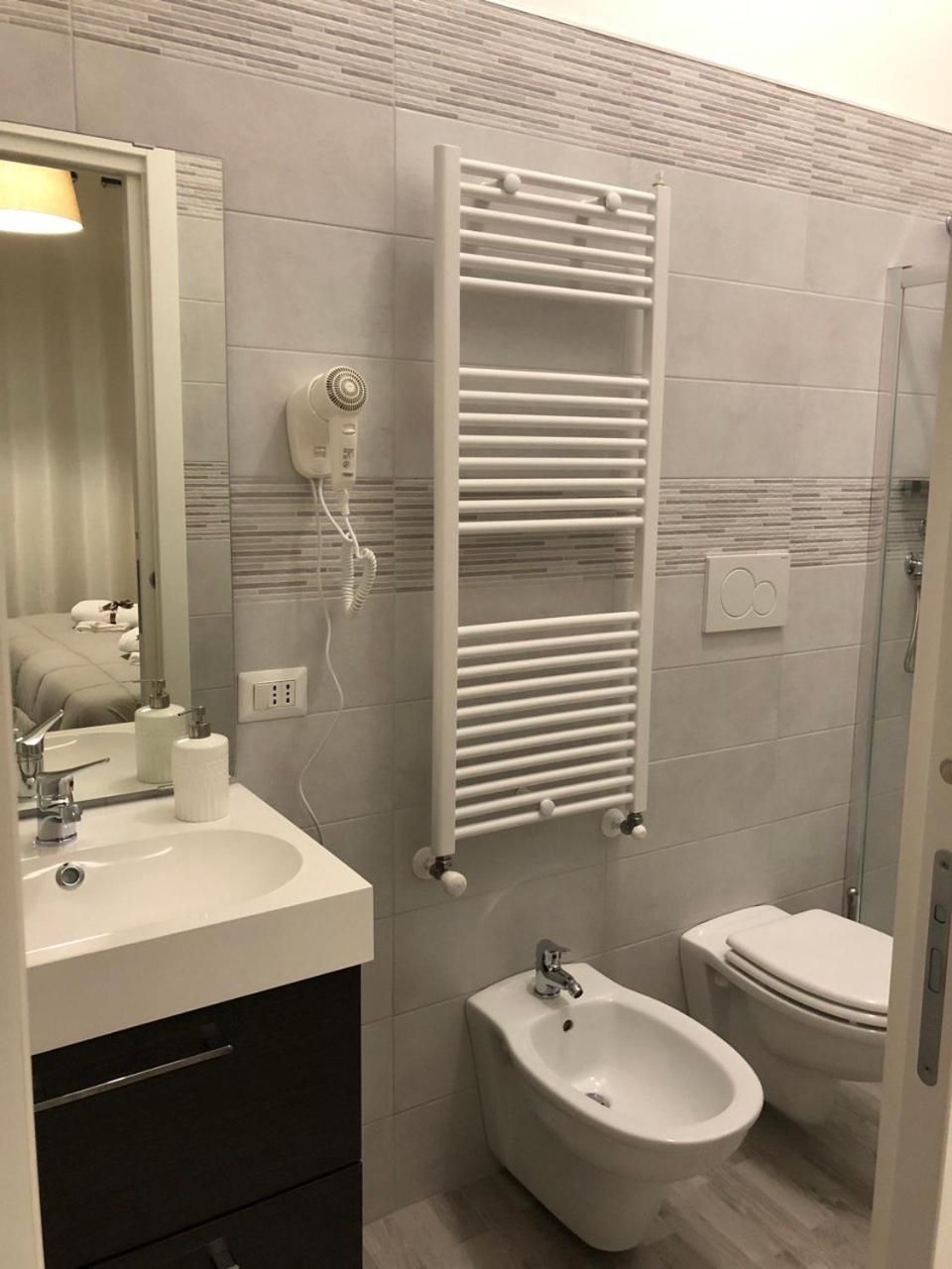 A modern bathroom with a white sink, bidet, and toilet.