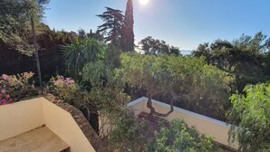 A balcony with a view of a lush garden and distant mountains. - STANDING villa, 450m from the BEACHES, heated SWIMMING POOL, SUPERB SEA VIEW, beautiful garden (Le Lavandou)