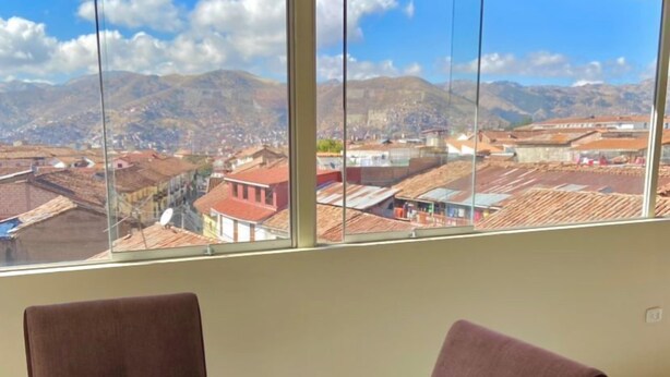 A breakfast setup with a table, chairs, and a view of a cityscape through large windows.