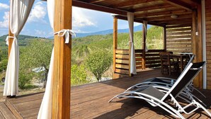 Une terrasse en bois dotée d’un espace couvert, de chaises en bois et d’une table.