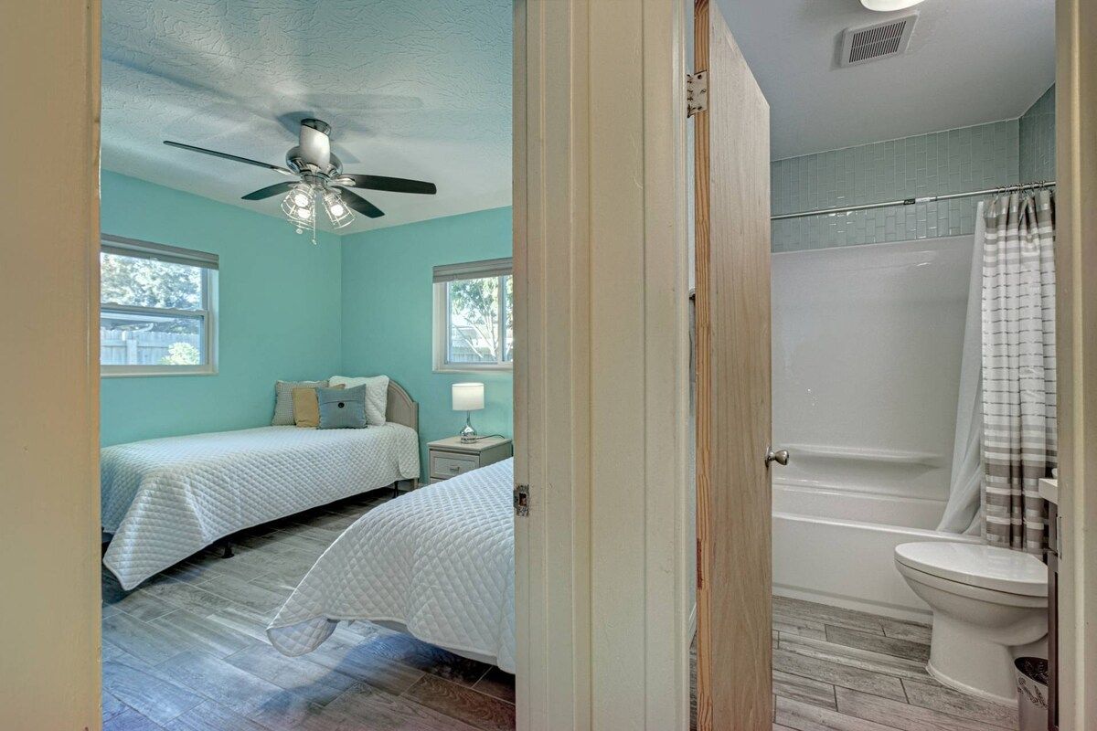 A bedroom with two beds, a ceiling fan, and a nightstand with a lamp.