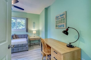 Une chambre à coucher comprenant un lit, un bureau, une chaise, une lampe, une horloge murale et une citation inspirante.