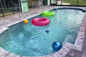 A swimming pool with inflatable rings and a blue buoy.