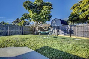 Un jardin avec une clôture en bois, un hamac et un arbre.
