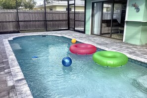 Une piscine avec trois bouées gonflables et un ballon.