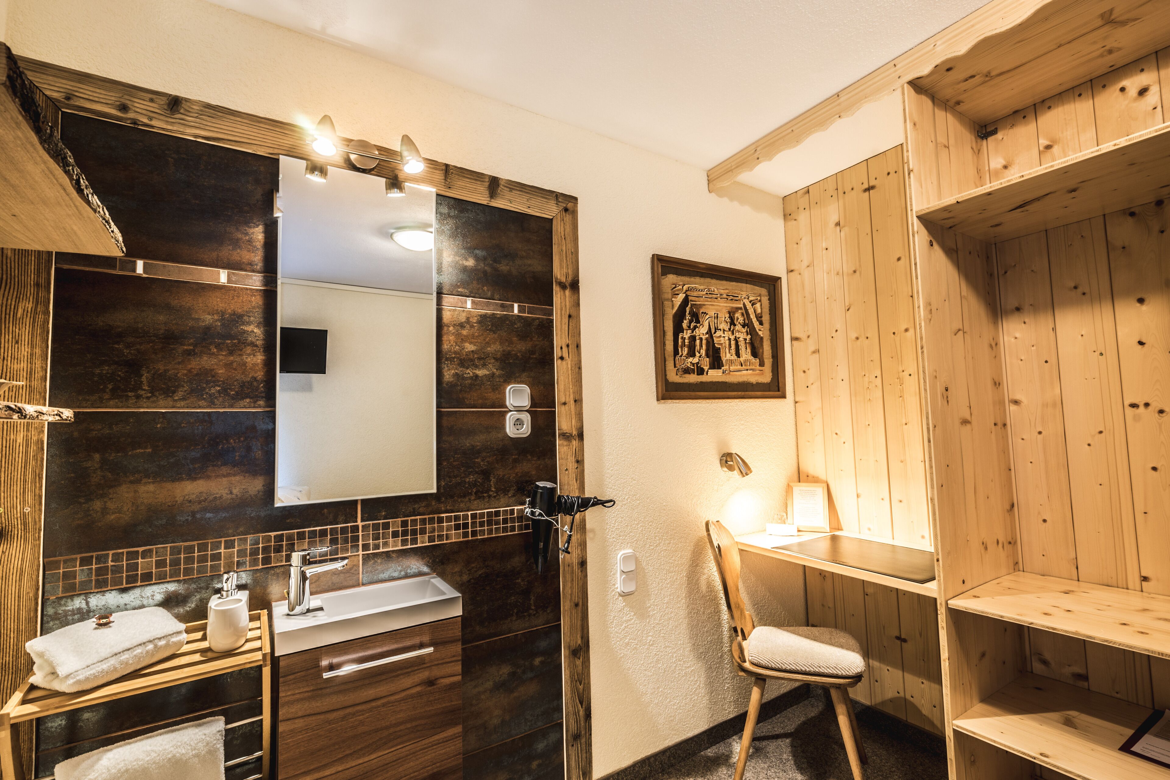 A bathroom with a wooden vanity, a large mirror, and a towel rack.