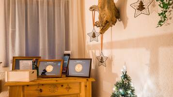 A wooden dresser with framed awards, a small Christmas tree, and star decorations against a wall.
