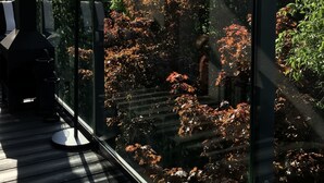 A balcony with a glass railing, a barbecue grill, and a view of trees and foliage. - Apartment Piękna4U 116 m2 (Śródmieście)