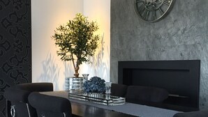 A modern dining area with a black table, four chairs with pearl-studded details, a large wall clock, and a potted plant. - Apartment Piękna4U 116 m2 (Śródmieście)