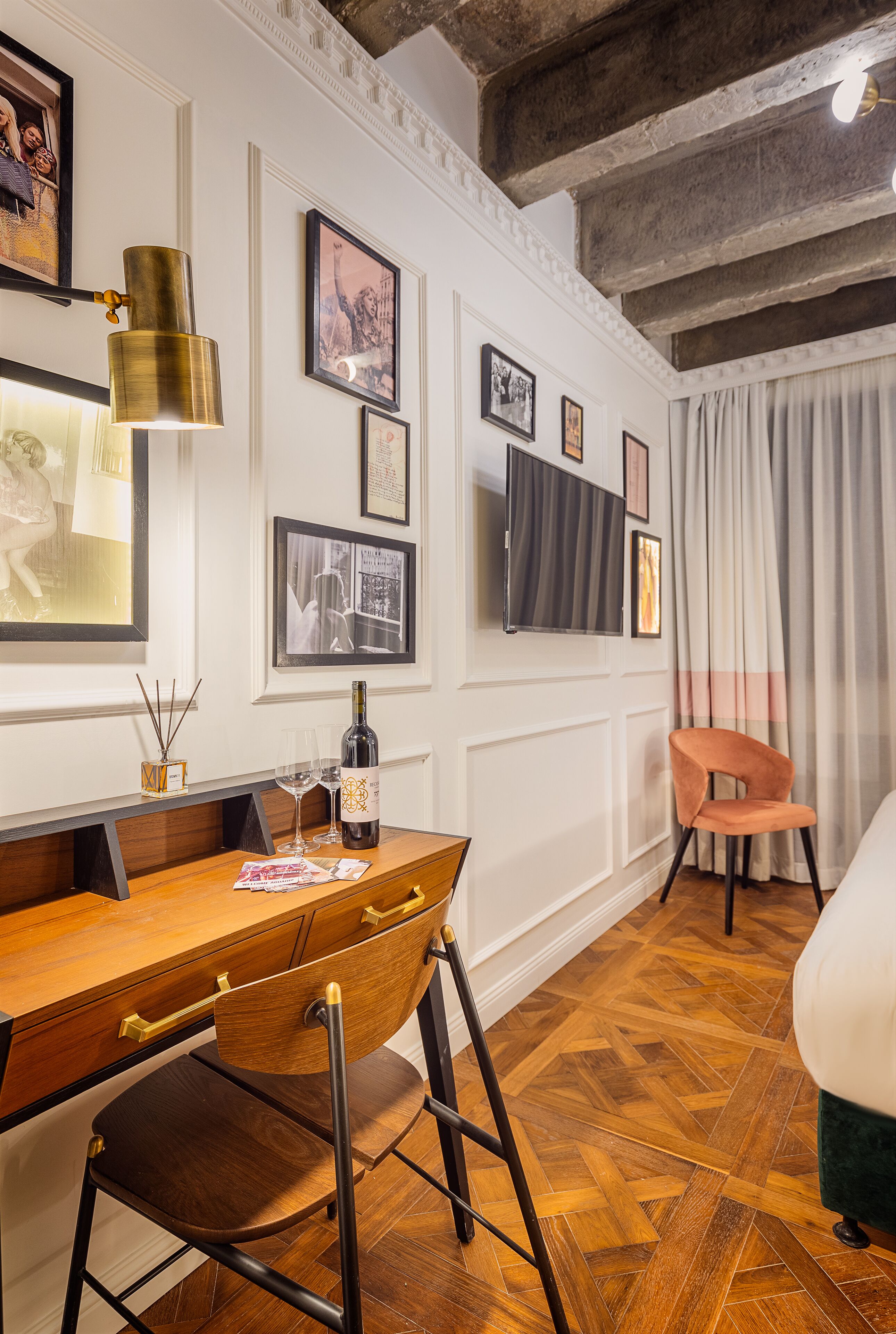 Ein Zimmer mit einem Holzesstisch, einem Stuhl, einer Weinflasche und einem an der Wand befestigten Fernseher.
