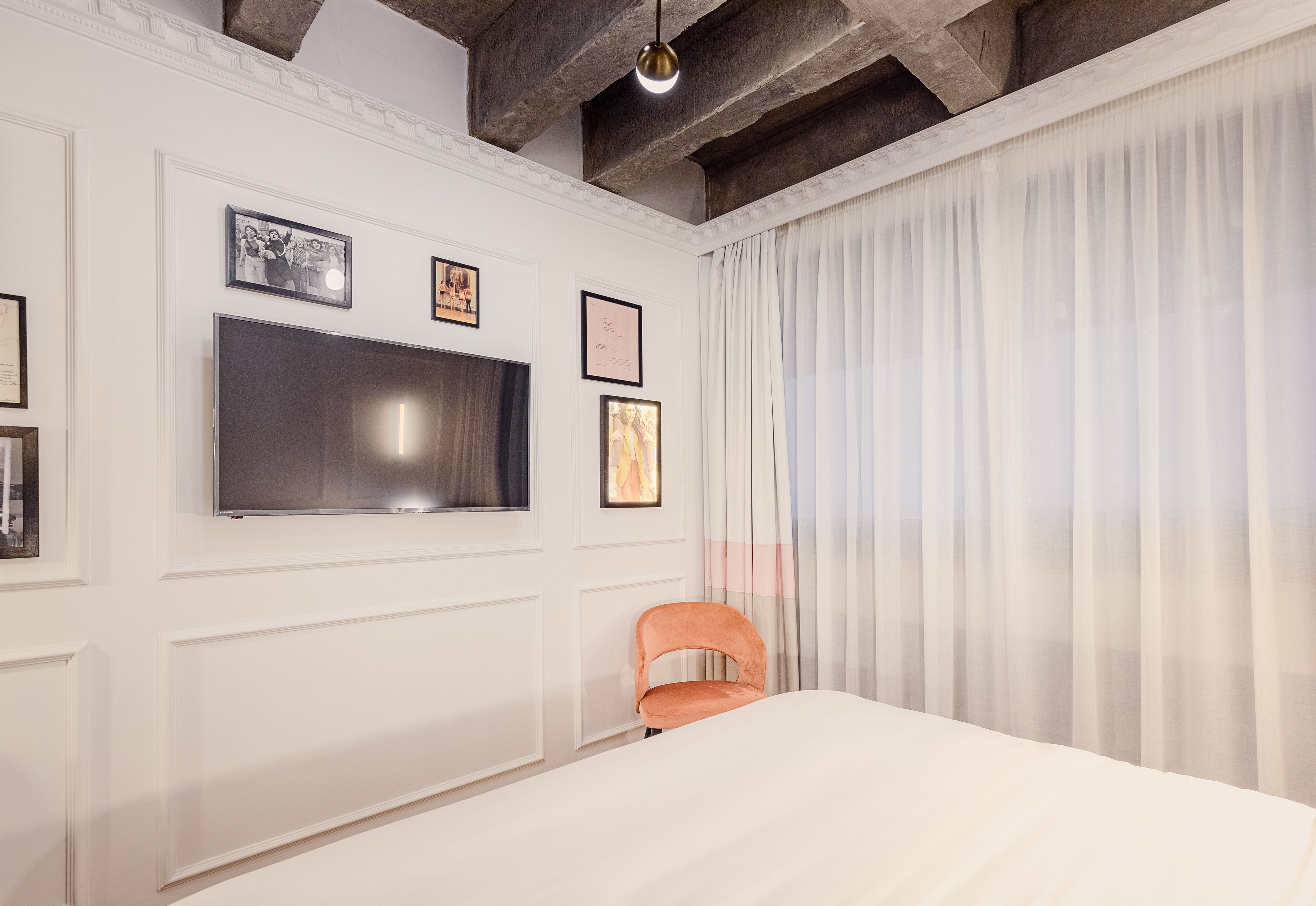 A bedroom with a bed, a television mounted on the wall, and a chair.