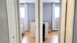 A hallway with a tiled floor leading to two rooms with white walls and a window with curtains. - Thien May Guest House. Up to 6 guests (Surrey)
